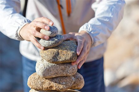 powerful small - caucasian young person stacking stones at the beach Stock Photo - Budget Royalty-Free & Subscription, Code: 400-07220868