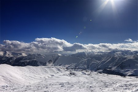 simsearch:400-07211845,k - Ski slope and blue sky with sun rays. Caucasus Mountains, Georgia, ski resort Gudauri. Wide angle view. Stockbilder - Microstock & Abonnement, Bildnummer: 400-07221326