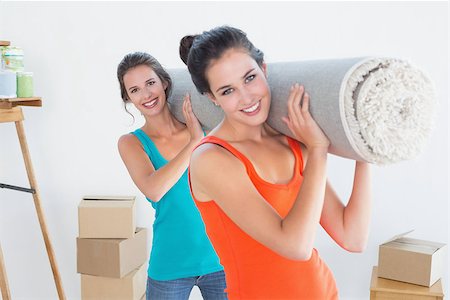 Portrait of two smiling female friends carrying rolled rug after moving in a house Stock Photo - Budget Royalty-Free & Subscription, Code: 400-07230526