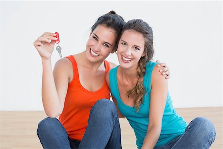 Portrait of two cheerful female friends with house keys sitting on the floor Stock Photo - Budget Royalty-Free & Subscription, Code: 400-07230537