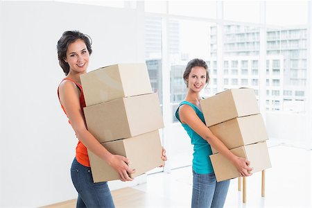 Portrait of two female friends carrying boxes in in a bright new house Stock Photo - Budget Royalty-Free & Subscription, Code: 400-07230556