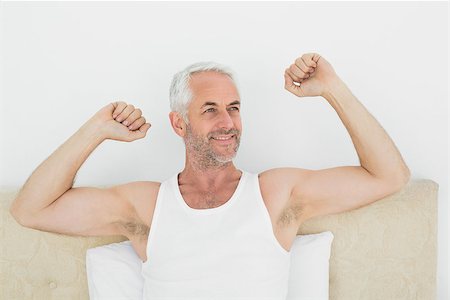 Mature smiling man stretching his arms in bed at home Stock Photo - Budget Royalty-Free & Subscription, Code: 400-07230594