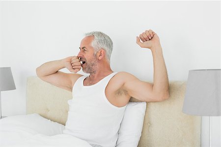 simsearch:614-06813544,k - Mature man waking up in bed and stretching his arms at home Stockbilder - Microstock & Abonnement, Bildnummer: 400-07230597