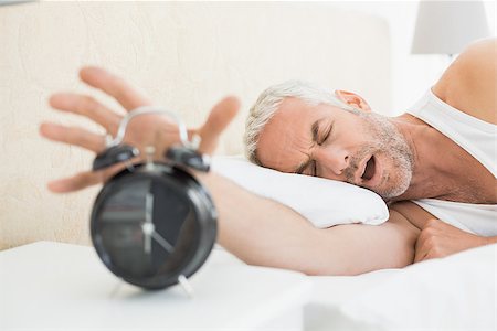 simsearch:614-02613098,k - Sleepy mature man extending hand to alarm clock in bed at home Stockbilder - Microstock & Abonnement, Bildnummer: 400-07230655