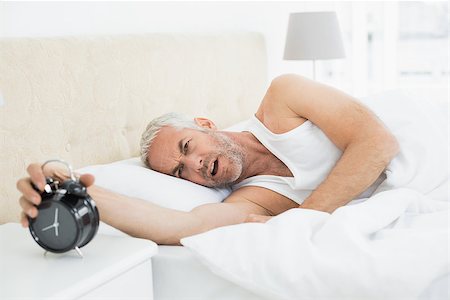 simsearch:614-02613098,k - Sleepy mature man extending hand to alarm clock in bed at home Stockbilder - Microstock & Abonnement, Bildnummer: 400-07230659