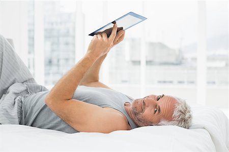 Portrait of a smiling mature man resting with digital tablet in bed at home Stock Photo - Budget Royalty-Free & Subscription, Code: 400-07230669