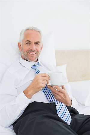 sophisticated home smile - Portrait of a smiling well dressed mature man with a cup of tea in bed at home Stock Photo - Budget Royalty-Free & Subscription, Code: 400-07230716