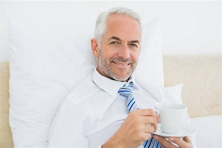 sophisticated home smile - Portrait of a smiling well dressed mature man with a cup of tea in bed at home Stock Photo - Budget Royalty-Free & Subscription, Code: 400-07230717
