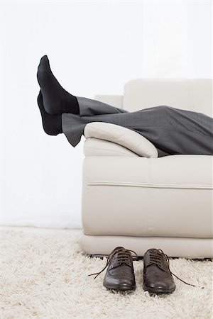 sock of businessman - Low section side view of a businessman resting on sofa in the living room at home Stock Photo - Budget Royalty-Free & Subscription, Code: 400-07230749