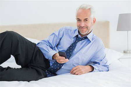 sophisticated home smile - Portrait of a smiling relaxed well dressed man text messaging in bed at home Stock Photo - Budget Royalty-Free & Subscription, Code: 400-07230743