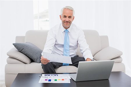 sophisticated home smile - Smiling mature businessman working on graphs and laptop in the living room at home Stock Photo - Budget Royalty-Free & Subscription, Code: 400-07230766