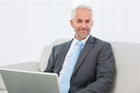sophisticated home smile - Portrait of a relaxed mature businessman with laptop sitting on sofa in living room at home Stock Photo - Budget Royalty-Free & Subscription, Code: 400-07230770