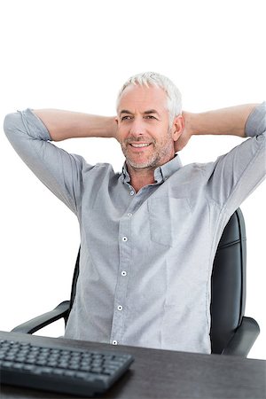 Relaxed mature businessman sitting with hands behind head at desk against white background Photographie de stock - Aubaine LD & Abonnement, Code: 400-07230799