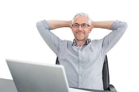 Relaxed mature businessman sitting with hands behind head and laptop against white background Photographie de stock - Aubaine LD & Abonnement, Code: 400-07230804
