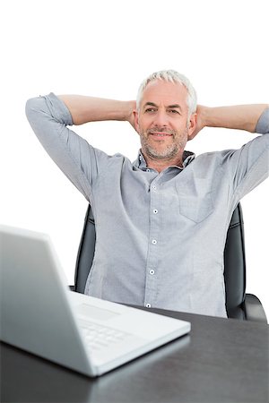 Relaxed mature businessman sitting with hands behind head with laptop against white background Stock Photo - Budget Royalty-Free & Subscription, Code: 400-07230802