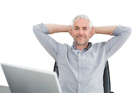 Relaxed mature businessman sitting with hands behind head with laptop against white background Stock Photo - Budget Royalty-Free & Subscription, Code: 400-07230803
