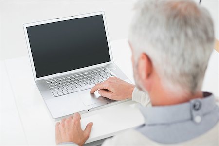simsearch:400-07230809,k - Close-up rear view of a grey haired man using laptop at desk against white background Foto de stock - Super Valor sin royalties y Suscripción, Código: 400-07230841