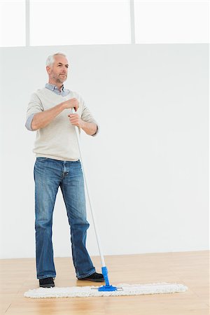 simsearch:400-07228658,k - Full length of a thoughtful mature man standing with a mop in a bright room Stockbilder - Microstock & Abonnement, Bildnummer: 400-07230858