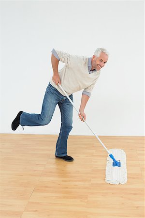 simsearch:400-07228658,k - Full length portrait of a cheerful mature man mopping the floor in a room Stockbilder - Microstock & Abonnement, Bildnummer: 400-07230864