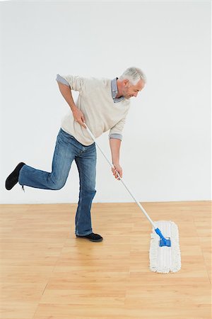 simsearch:400-07228658,k - Full length side view of a mature man mopping the floor in a room Stockbilder - Microstock & Abonnement, Bildnummer: 400-07230863