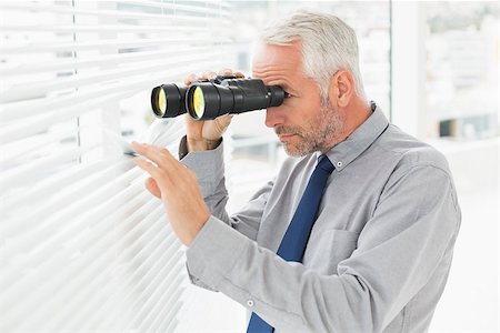 simsearch:400-07266908,k - Side view of a serious mature businessman peeking with binoculars through blinds in the office Photographie de stock - Aubaine LD & Abonnement, Code: 400-07230897