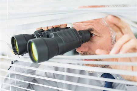 Close-up of a serious mature businessman peeking with binoculars through blinds in the office Stock Photo - Budget Royalty-Free & Subscription, Code: 400-07230906