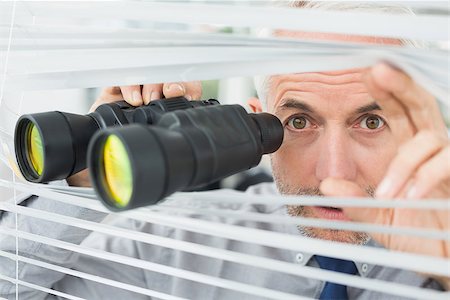 Close-up of a serious mature businessman peeking with binoculars through blinds in the office Stock Photo - Budget Royalty-Free & Subscription, Code: 400-07230907