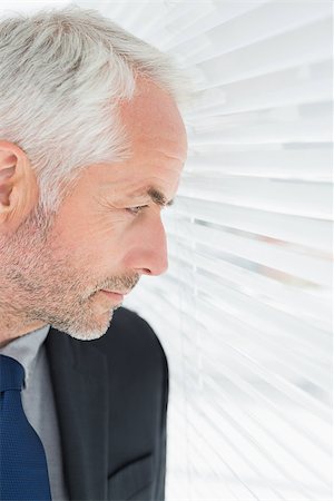Close-up of a serious mature businessman peeking through blinds in the office Stock Photo - Budget Royalty-Free & Subscription, Code: 400-07230920