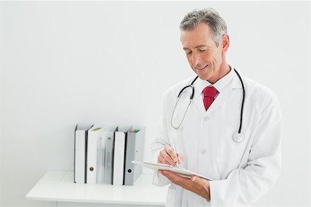 simsearch:614-06898452,k - Smiling male doctor writing a report at the medical office Stock Photo - Budget Royalty-Free & Subscription, Code: 400-07230957