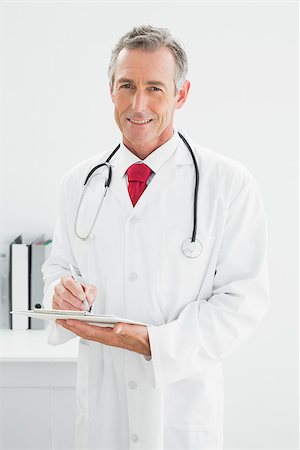 simsearch:614-06898452,k - Portrait of a smiling male doctor writing a report at the medical office Stock Photo - Budget Royalty-Free & Subscription, Code: 400-07230959