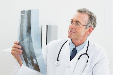 simsearch:400-07269250,k - Concentrated male doctor looking at x-ray picture of spine in the medical office Stock Photo - Budget Royalty-Free & Subscription, Code: 400-07231008