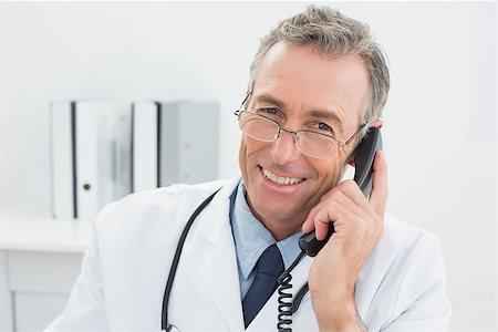 simsearch:614-06898452,k - Close-up portrait of a smiling male doctor using telephone at the medical office Stock Photo - Budget Royalty-Free & Subscription, Code: 400-07231003