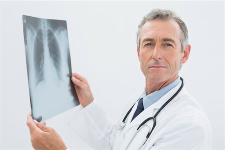 simsearch:400-07269250,k - Portrait of a confident male doctor with x-ray picture of lungs over white background Stock Photo - Budget Royalty-Free & Subscription, Code: 400-07231019