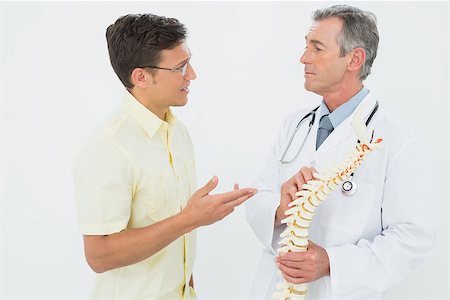 doctor bone model - Male doctor showing patient something on skeleton model over white background Stock Photo - Budget Royalty-Free & Subscription, Code: 400-07231044