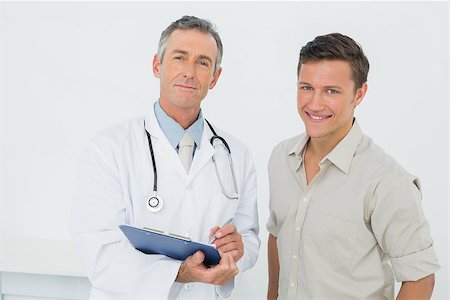 simsearch:614-06898452,k - Portrait of a male doctor and patient with reports standing in medical office Stock Photo - Budget Royalty-Free & Subscription, Code: 400-07231068