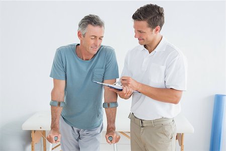 Male therapist discussing reports with a disabled patient in the gym at hospital Photographie de stock - Aubaine LD & Abonnement, Code: 400-07231093