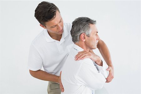 Side view of a male chiropractor examining mature man over white background Stockbilder - Microstock & Abonnement, Bildnummer: 400-07231186