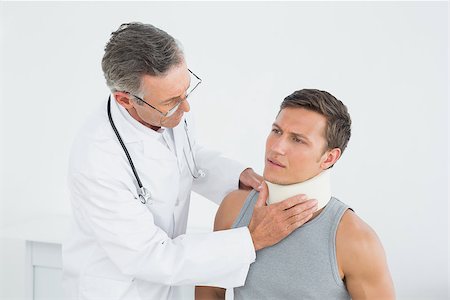 simsearch:400-07269643,k - Male doctor examining a patients neck in the medical office Fotografie stock - Microstock e Abbonamento, Codice: 400-07231196