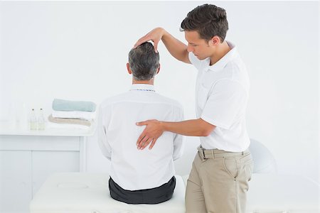 Rear view of a male chiropractor examining mature man at office Stockbilder - Microstock & Abonnement, Bildnummer: 400-07231190