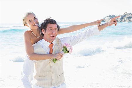 simsearch:400-07664797,k - Newlyweds pointing to something smiling at camera at the beach Stock Photo - Budget Royalty-Free & Subscription, Code: 400-07231304