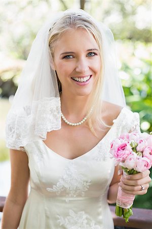 Smiling bride in a veil holding her bouquet looking at camera in the countryside Stock Photo - Budget Royalty-Free & Subscription, Code: 400-07231361