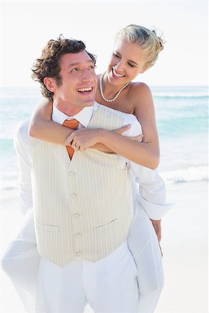 simsearch:400-07664797,k - Smiling bride getting a piggy back from husband at the beach Stock Photo - Budget Royalty-Free & Subscription, Code: 400-07231535