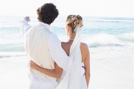 simsearch:400-07664797,k - Newlyweds standing by the sea with husband pointing at the beach Stock Photo - Budget Royalty-Free & Subscription, Code: 400-07231544