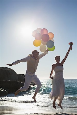 simsearch:400-07664797,k - Groom holding balloons and bride holding bouquet jumping at the beach Stock Photo - Budget Royalty-Free & Subscription, Code: 400-07231548