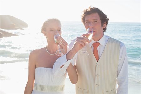Young newlyweds drinking champagne linking arms at the beach Photographie de stock - Aubaine LD & Abonnement, Code: 400-07231555