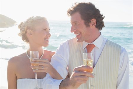 simsearch:400-07664797,k - Young newlyweds having champagne linking arms at the beach Stock Photo - Budget Royalty-Free & Subscription, Code: 400-07231556