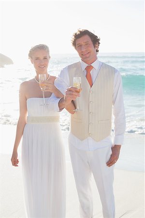 simsearch:400-07664797,k - Happy newlyweds having champagne linking arms at the beach Stock Photo - Budget Royalty-Free & Subscription, Code: 400-07231557