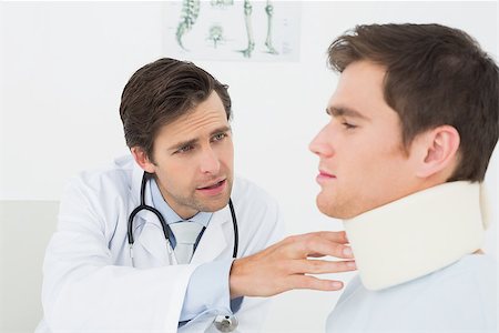 simsearch:400-07269643,k - Male doctor examining a patients sprained neck at medical office Fotografie stock - Microstock e Abbonamento, Codice: 400-07231949