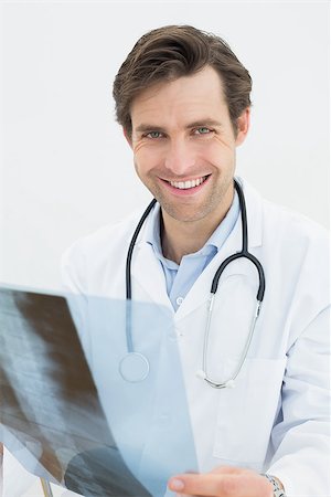 simsearch:400-05088220,k - Portrait of a smiling male doctor examining spine x-ray over white background Stock Photo - Budget Royalty-Free & Subscription, Code: 400-07231967