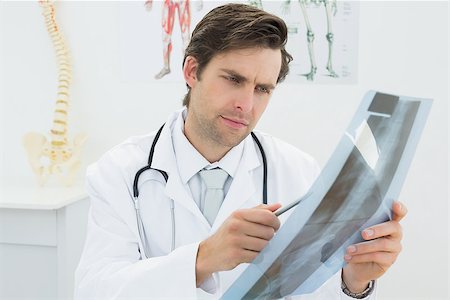 simsearch:400-07269250,k - Concentrated male doctor looking at x-ray picture of spine in the medical office Stock Photo - Budget Royalty-Free & Subscription, Code: 400-07231980